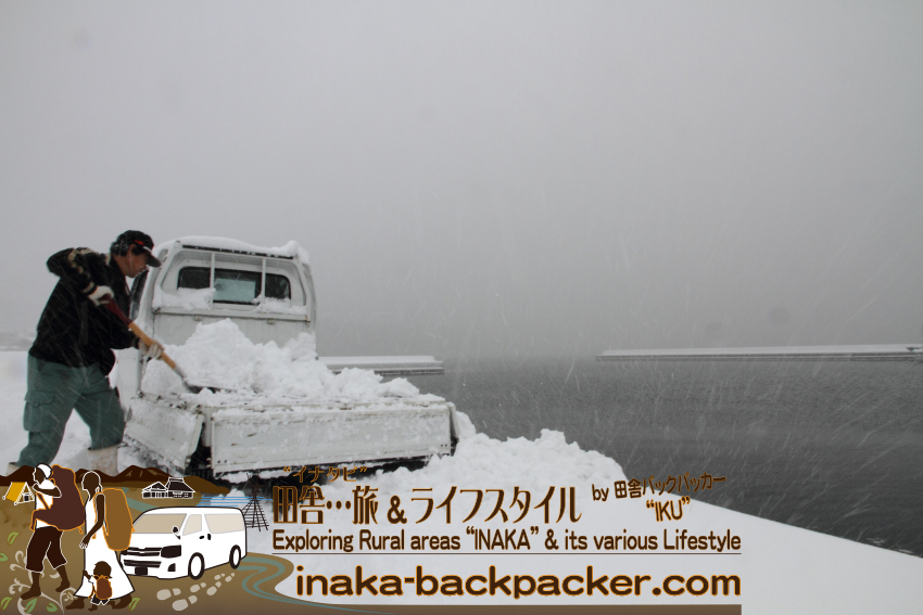 雪降る穴水町岩車で、軽トラックに積った雪を海に落としている